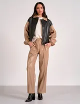 Pantalón de eco cuero color marrón, marca Elan, con pretina elastizada, bolsillos delanteros, pierna recta y costura frontal.