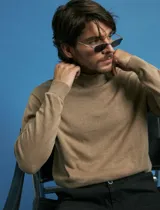 Polera de cuello alto en color beige, confeccionada en tejido de punto fino, con mangas largas y puños acanalados.