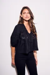Blusa negra de algodón peinado con calce oversize, escote en V, mangas tres cuartos abullonadas y detalles de encaje y bordados en el frente y mangas.