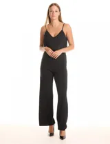 Enterito negro de crepe con escote en V, breteles finos ajustables y una capa suelta en la parte superior. La cintura es definida con corte anatómico y el pantalón tiene pierna ancha de caída fluida. Cierre invisible en la espalda.