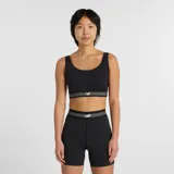 Top deportivo de alto rendimiento con diseño de escote redondo y espalda estilo nadadora. Presenta una banda elástica inferior con rayas horizontales y el logo de la marca. Confeccionado en tejido técnico transpirable de secado rápido, ideal para actividades de impacto moderado. Incluye copas extraíbles.