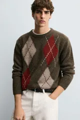 Jersey de punto con lana, corte relajado, cuello redondo y manga larga. Presenta un diseño de rombos en tonos marrón, beige y rojo con detalles bordados, y acabados en rib.