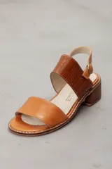 Sandalia de cuero vacuno color tostado con taco bajo y ancho, tira frontal lisa y tira ancha con textura de cocodrilo en el empeine, y tira ajustable al talón con hebilla metálica.
