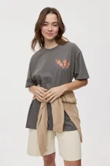 Remera de manga corta con calce oversized y cuello redondo, color gris oscuro, con pequeño gráfico de rayos naranjas en el frente.