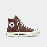 Championes Converse modelo Chuck 70, de caña alta, confeccionados en lona color marrón con suela de goma blanca y puntera reforzada. Presentan el icónico parche circular con el logo de la marca en el lateral interno, cordones blancos y costuras reforzadas.