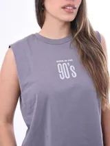 Remera sin mangas, color rosa claro, con cuello redondo y dobladillo inferior con terminación deshilachada. Presenta un pequeño estampado de trébol de cuatro hojas en color verde menta con texto debajo.