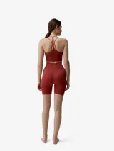 Short deportivo de tejido seamless en color rojo, tiro alto y diseño ajustado con detalles de perforaciones laterales y pequeño logo reflectante.