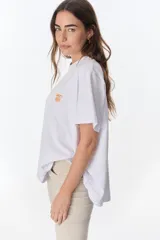 Remera blanca de algodón con estampado frontal en azul que dice "The flowers Club" y un diseño de flores de loto.