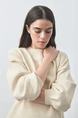 Sweater de tejido liviano con silueta relajada, hombros caídos y mangas largas con puños ajustados. Presenta cuello redondo y lazos ajustables en el bajo.