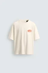 Camiseta de corte relajado color crudo, con cuello redondo y manga corta. Presenta un estampado gráfico pequeño en el pecho y un diseño grande en la espalda relacionado con el artista Post Malone.